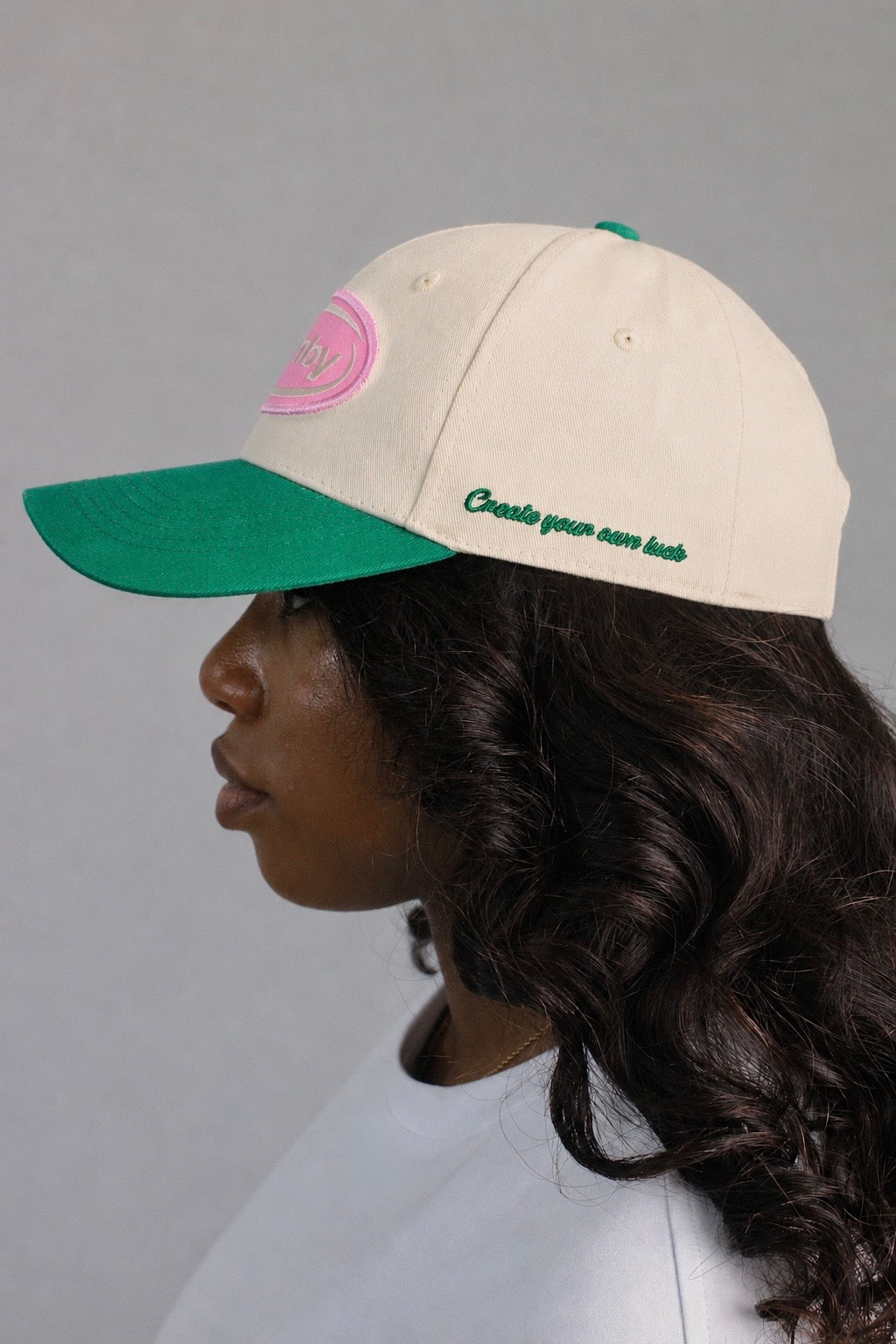 Side view of hamby baseball SnapBack cap. Embroidery quote on left panel, pink logo patch on the front with green visor. 