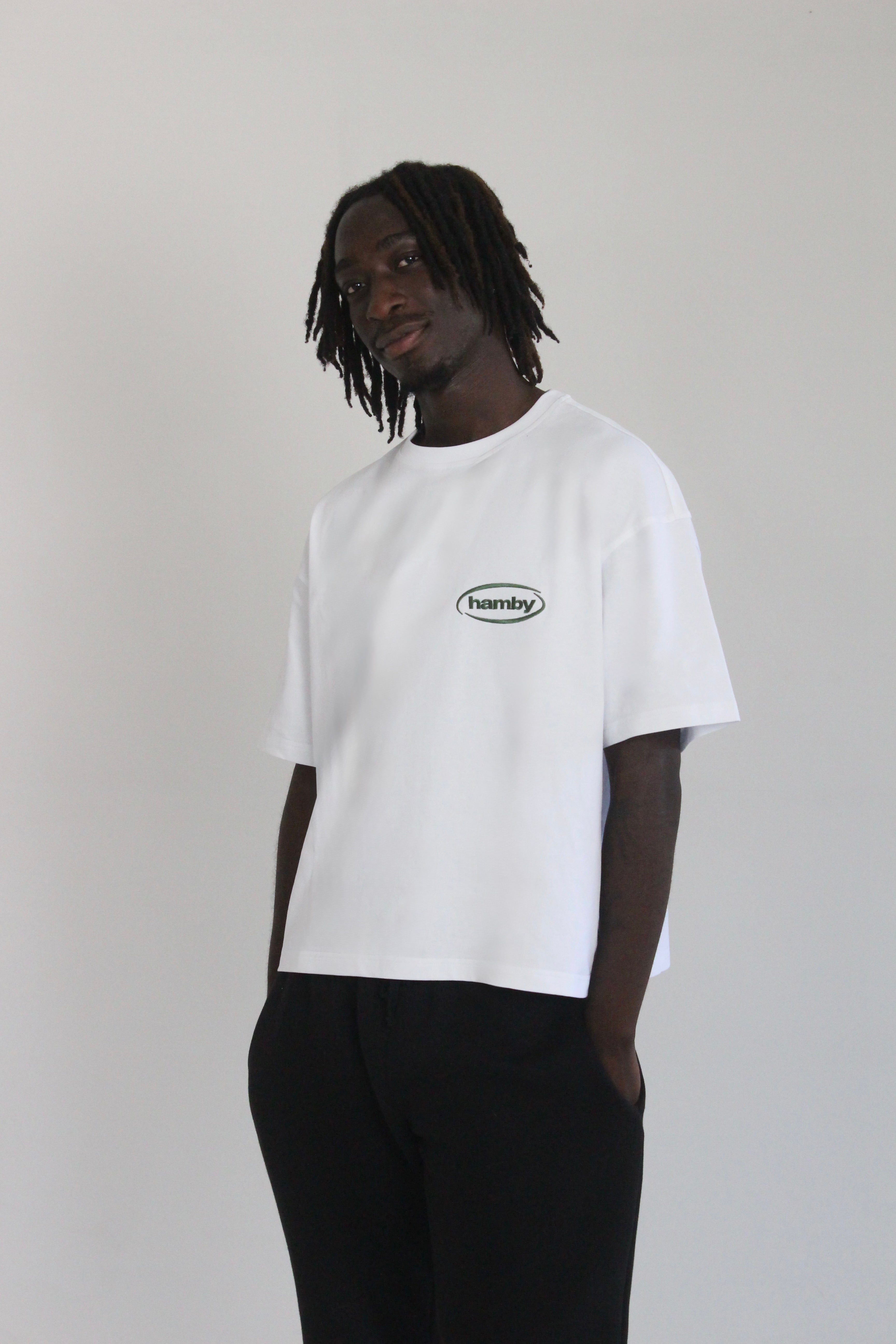 Model wearing hamby’s roll the dice tee in white. Oversize, boxy fit, 240gsm, 100% cotton. Hamby logo embroidered in green on front left chest. 