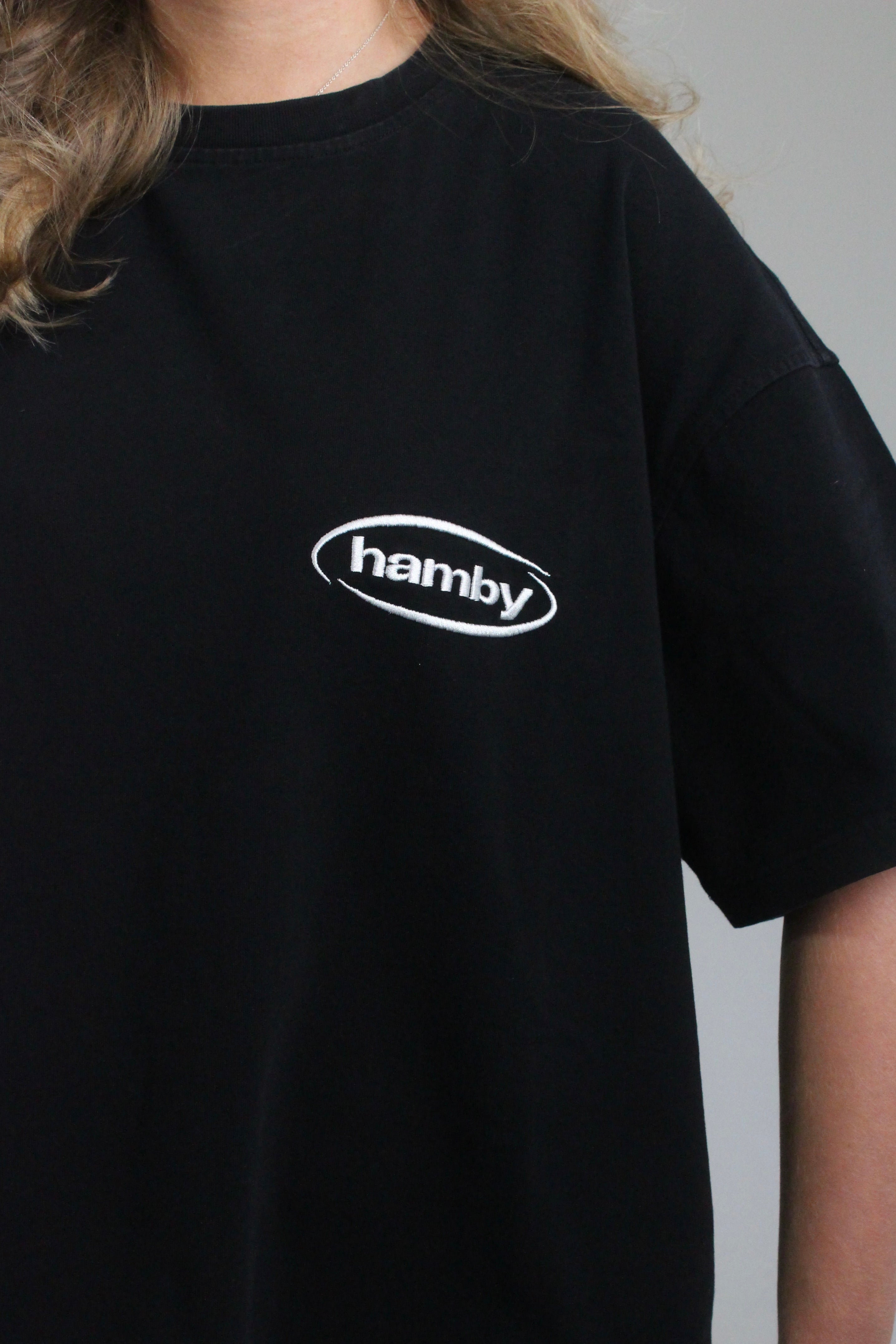 Close up of white hamby logo on the black hamby roll the dice tee. 
