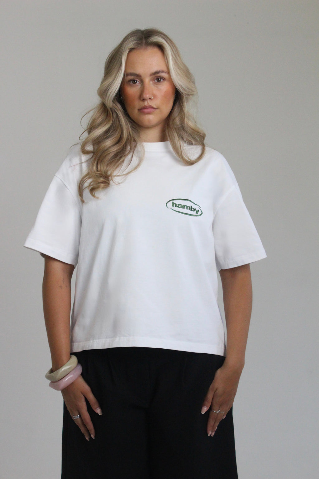 Model wearing hamby’s roll the dice tee in white. Oversize, boxy fit, 240gsm, 100% cotton. Hamby logo embroidered in green on front left chest. 