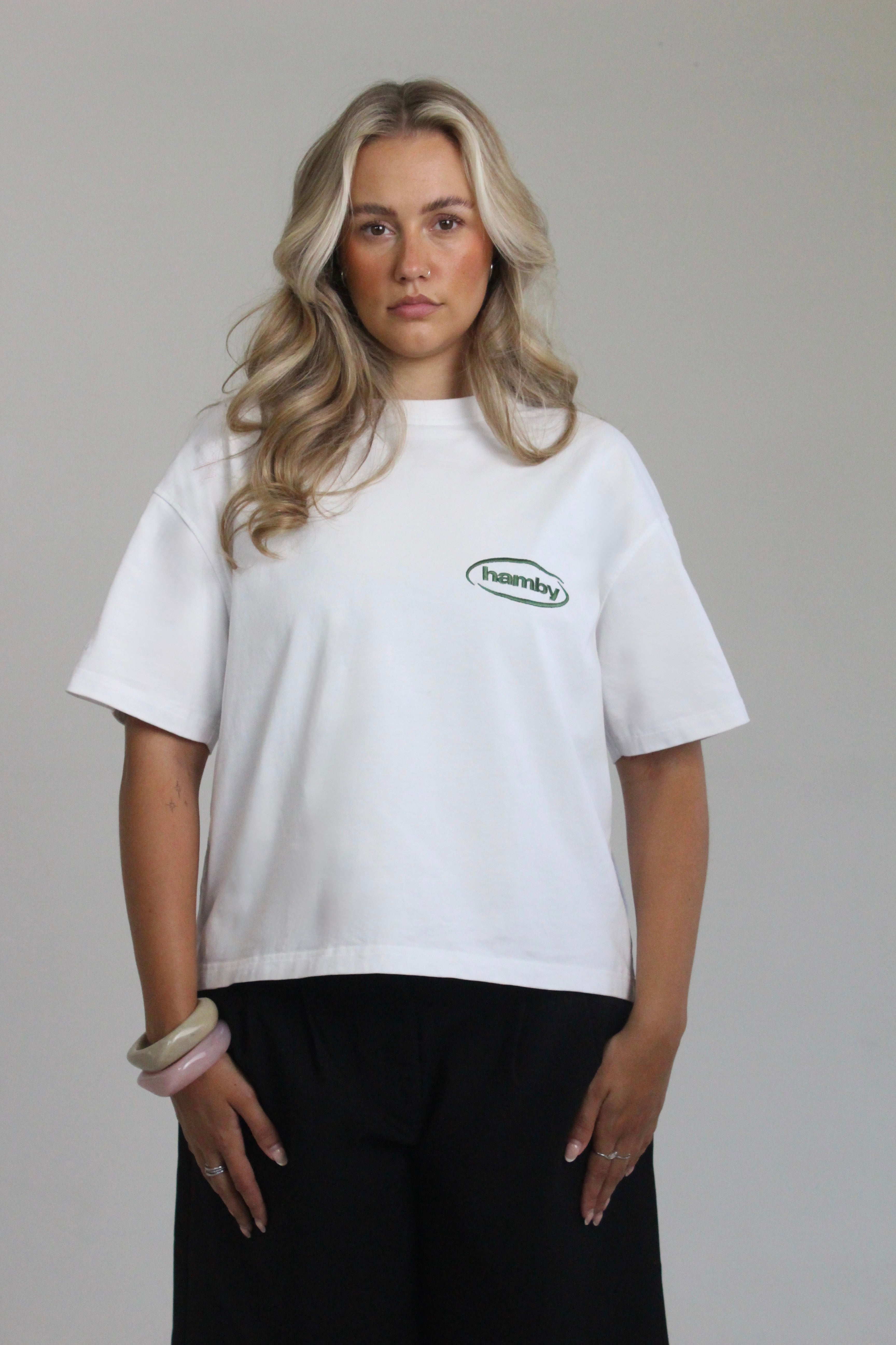 Model wearing hamby’s roll the dice tee in white. Oversize, boxy fit, 240gsm, 100% cotton. Hamby logo embroidered in green on front left chest. 